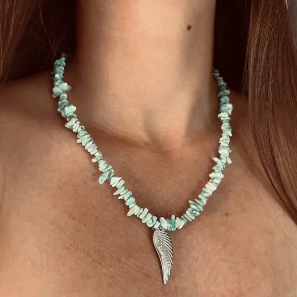 Larimar náhrdelník sekaný. Ukážka na krku. bledomodré úlomky kameňa ozdobené anjelskym krídlom strebornej farby.