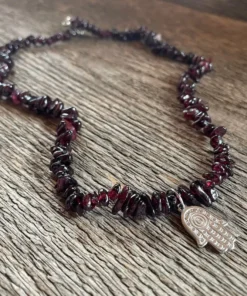 Náhrdelník GRANÁT ALMANDIN Hamsa. úlomky tmavobordového kameňa navlečené na silónovom lanku a v strede strieborná hamsa.