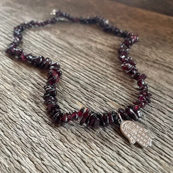 Náhrdelník GRANÁT ALMANDIN Hamsa. úlomky tmavobordového kameňa navlečené na silónovom lanku a v strede strieborná hamsa.