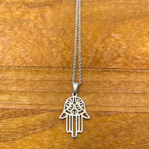 HAMSA náhrdelník z chirurgickej ocele. strieborná ruka s piatimi prstami, pričom palec a ukazovák sú k sebe otočené. V strede dlane je vyrezaný ornamentový vzor.